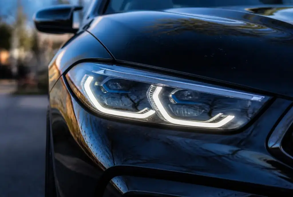 Glossy black BMW M8 headlight detailed to a mirror finish by FreshWorks Detailing in Manassas, VA